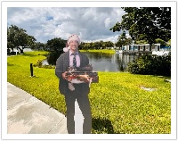 Clark Griswold from the movie National Lampoons Christmas Vacation holding a bundle of books in front of the main Lynn University lake